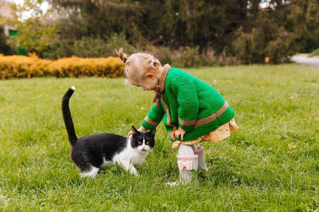 Klein meisje dat een zwarte kat in het park aait. meisje dat een kat aait. kinderen en dieren.