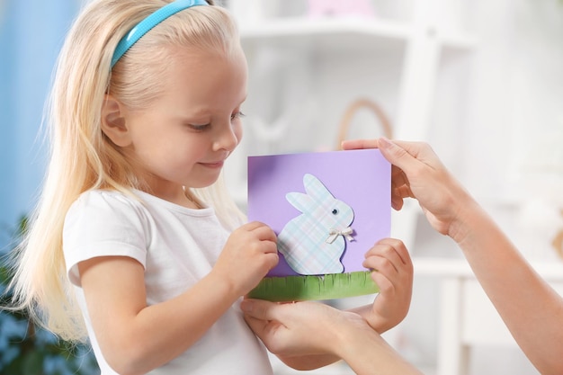 Klein meisje dat handgemaakte paaskaart presenteert aan haar moeder