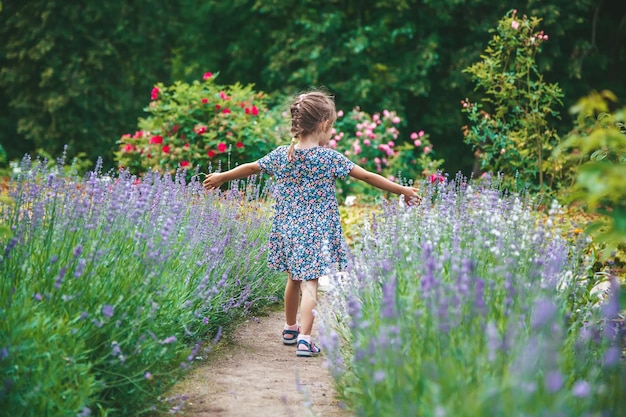 Klein meisje dat in een bloeiende zomertuin loopt