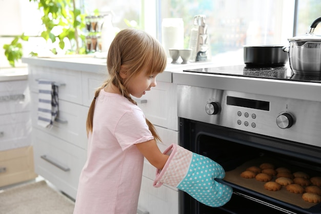 Klein meisje dat koekjes uit de oven haalt