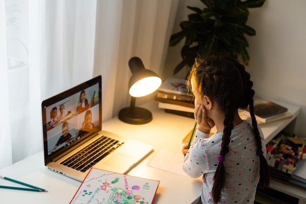 Klein meisje dat online studeert met haar laptop thuis