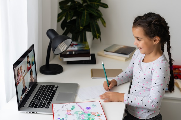 Klein meisje dat online studeert met haar laptop thuis