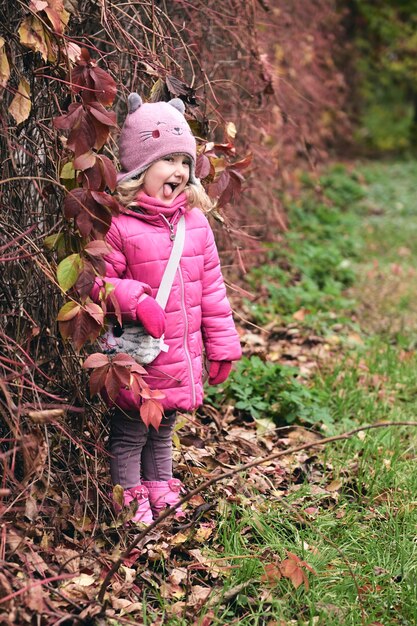 Klein meisje dat plezier heeft in een prachtig park met droge gele en rode bladeren, herfstfamiliewandeling in het bos