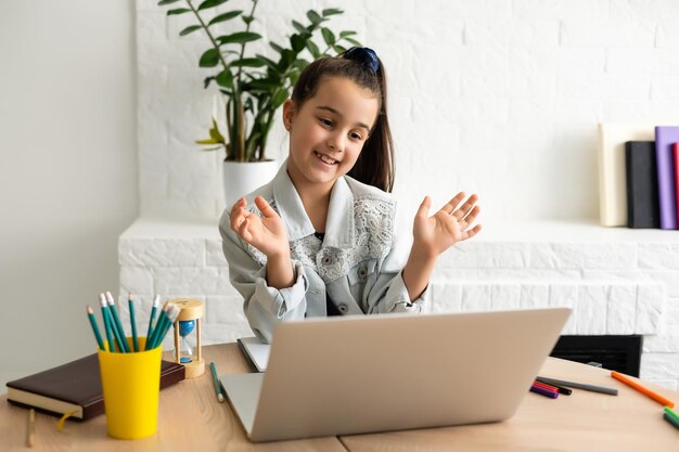 Klein meisje dat thuis deelneemt aan online e-learningplatformklas terwijl de school gesloten is tijdens de uitbraak van het coronavirus.