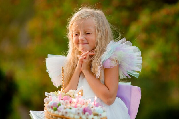 klein meisje doet een wens en blaast de kaarsen op de taart