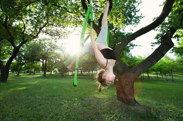 Klein meisje doet yoga-oefeningen met een hangmat in het park