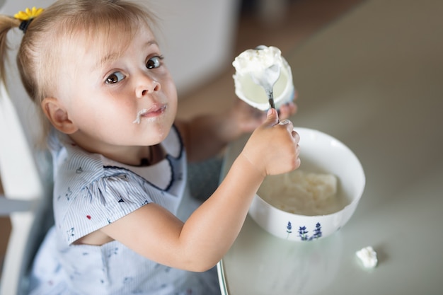 Klein meisje eet een lepel ijs van een bord