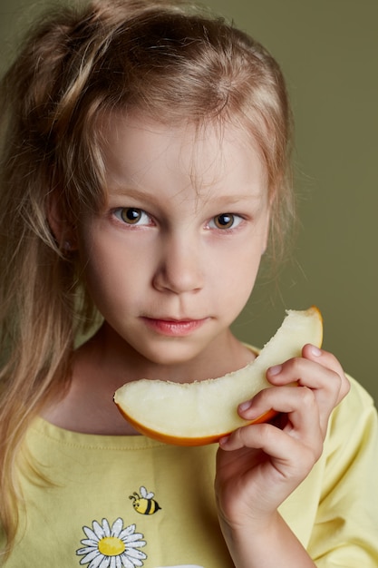 Klein meisje eet een meloen op groen