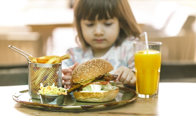 Klein meisje eet in een fastfood-café