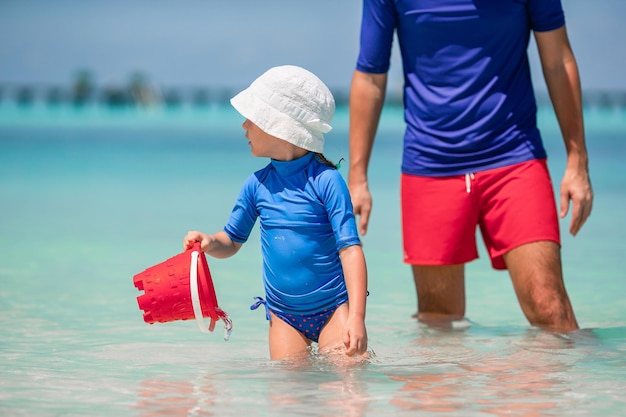 Klein meisje en gelukkige vader die plezier hebben tijdens strandvakantie