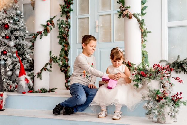 Klein meisje en haar broer openen kerstcadeautjes. Op de trappen van het nieuwjaarshuis