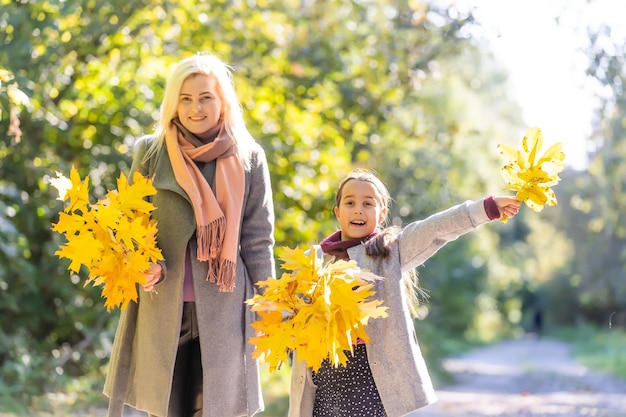 Klein meisje en haar moeder genieten van zonnig weer in het herfstpark.