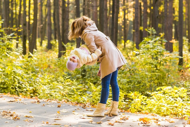 Klein meisje en haar moeder spelen in het herfstpark.