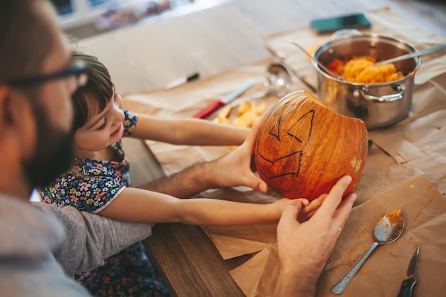 Klein meisje en haar vader houden een Halloween-pompoen vast