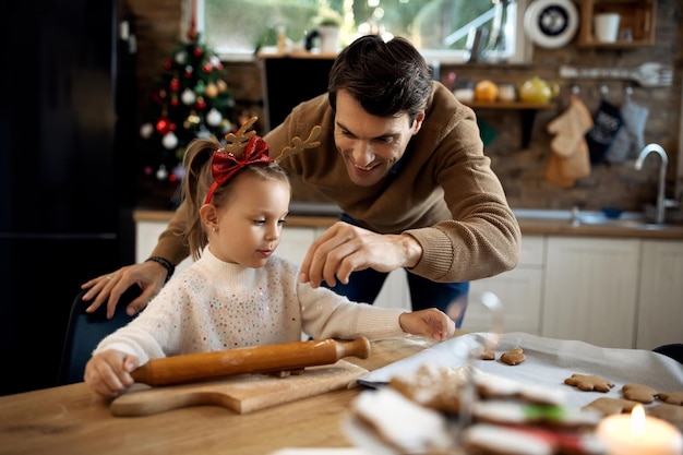 Klein meisje en haar vader maken koekjes op eerste kerstdag in de keuken