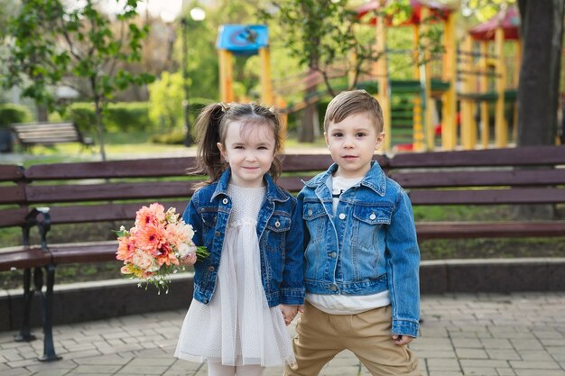 Klein meisje en jongen in het park met een boeket bloemen.