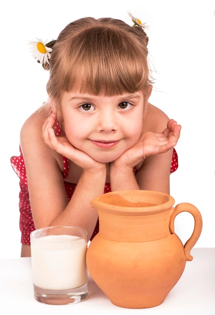 Klein meisje en melk klein schattig meisje met kruik van klei met melk geïsoleerd op de witte achtergrond