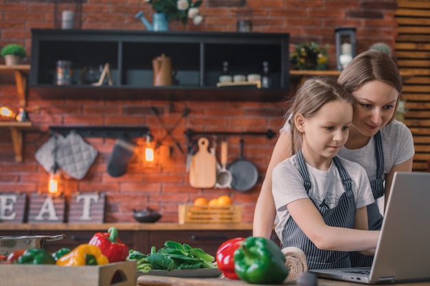 Klein meisje en moeder op laptop op keuken