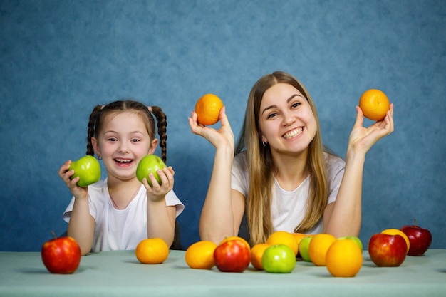 Klein meisje en moeder spelen met fruit en rotzooien. Ze dragen t-shirts