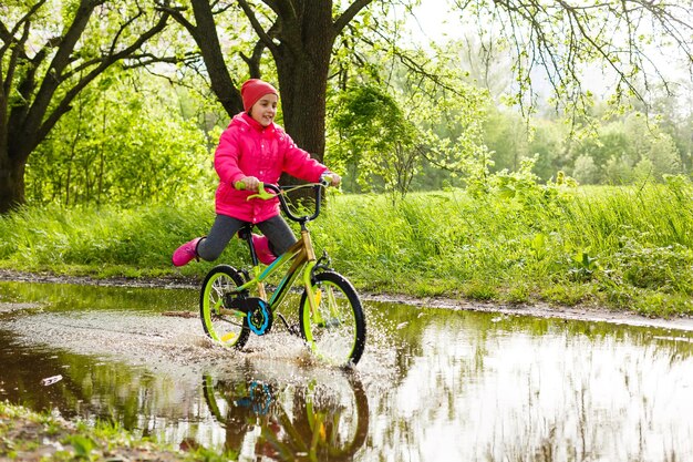 klein meisje fietst in waterplas