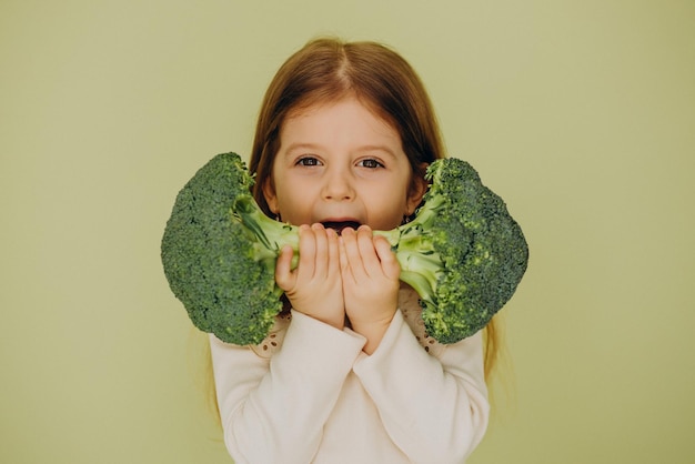 Klein meisje geïsoleerd met groene rauwe broccoli