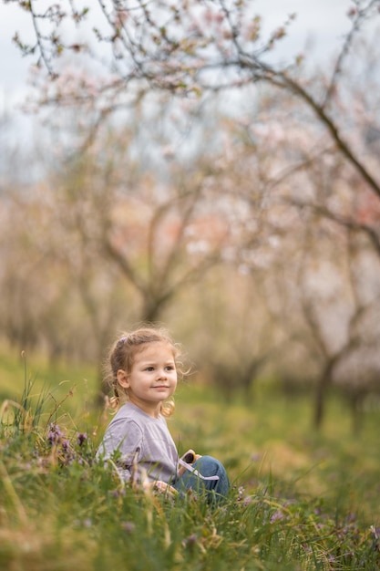 Klein meisje geniet van een mooie en zonnige lentedag in de buurt van bloeiende appelboom in het praagse park