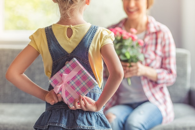 Foto klein meisje houdt een geschenkdoos voor haar mooie moeder.