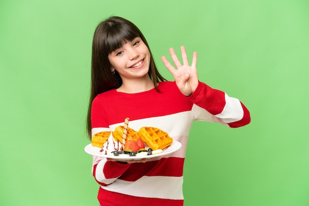 Klein meisje houdt wafels over geïsoleerde chroma key achtergrond gelukkig en telt vier met vingers