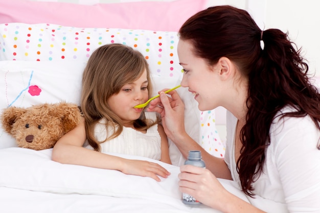 Klein meisje in bed nemen stroop