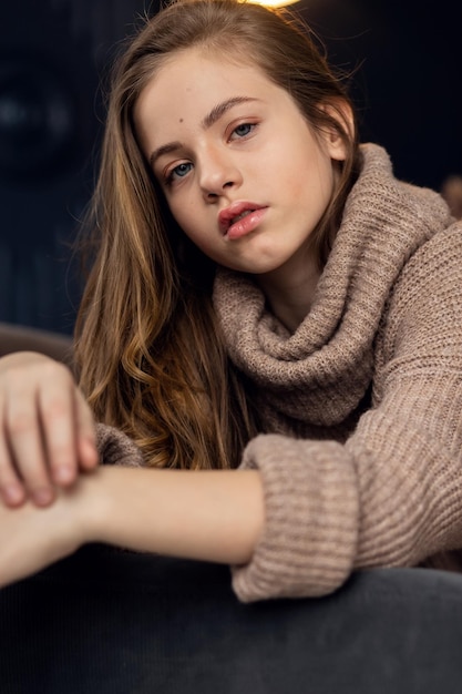 Klein meisje in bruine trui Schattig klein meisje in herfstkleren Portret van een lachend klein mooi meisje met lang haar Meisje 79 jaar oude handen op het gezicht