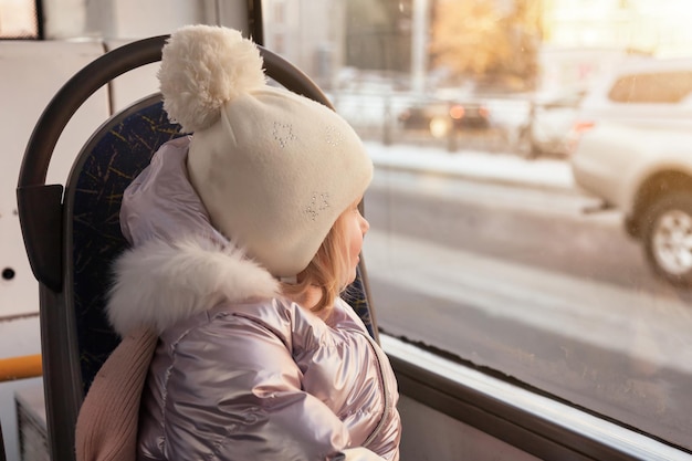 Klein meisje in bus kijken bij raam van openbaar stadsvervoer