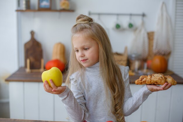 Klein meisje in de keuken die thuis een appel eet