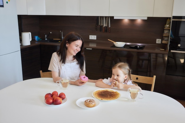 Klein meisje in de keuken eet pannenkoeken