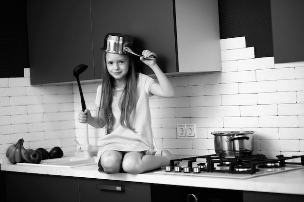 Klein meisje in de keuken met kookgerei