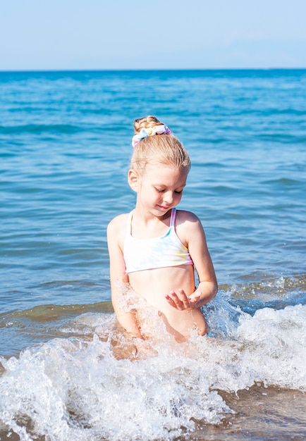 Klein meisje in een badpak spelen op het strand aan zee