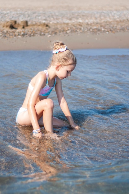 Klein meisje in een badpak spelen op het strand aan zee