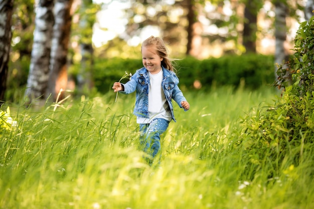 klein meisje in een denim pak loopt in de lente in de lila tuin