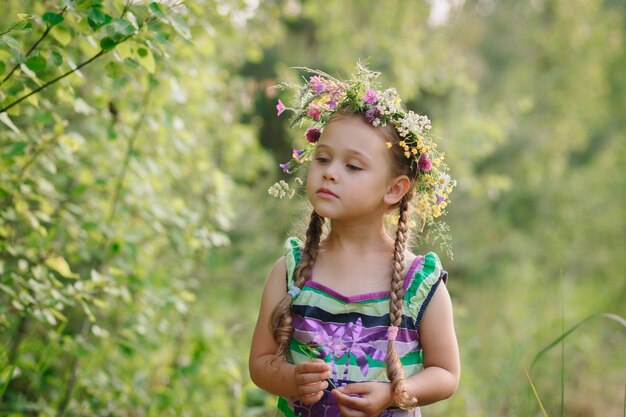 klein meisje in een krans van wilde bloemen in de zomer