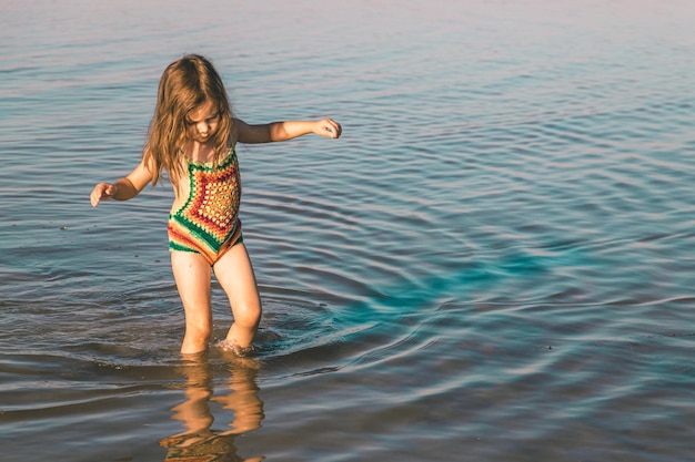 Klein meisje in gebreid zwempak is niet tevreden met het koude zeewater