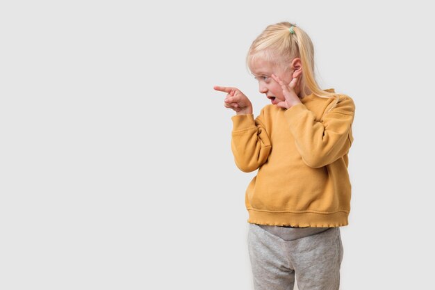 Klein meisje in gele capuchon wijst met de vinger naar de kopieerruimte