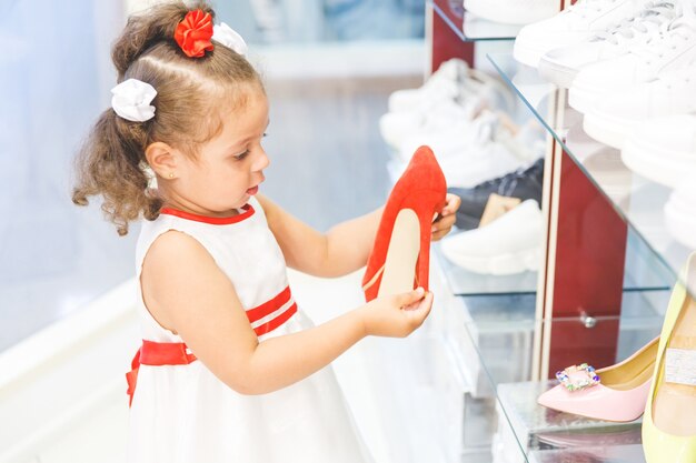 Klein meisje in het winkelcentrum kiest schoenen