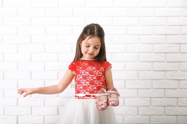 Foto klein meisje in jurk op een witte bakstenen muur achtergrond
