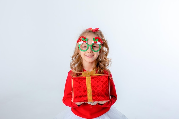 Klein meisje in kerstmuts houdt een geschenk op witte achtergrond Kerstmis concept tekstruimte