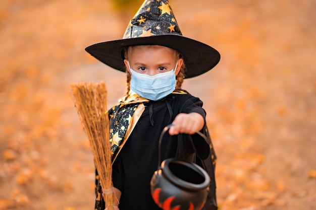 Foto klein meisje in kostuum van hoed in het park happy halloween coronavirus covid19 pandemische quarantaine