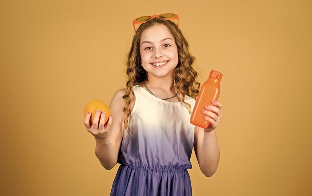 Klein meisje in mode bril verfrissend vitaminesap Gezondheidszorg Zomer vitamine dieet Natuurlijke vitaminebron gelukkig meisje drinken vers sinaasappelsap zomervakantie Genieten van nieuwe geweldige dag