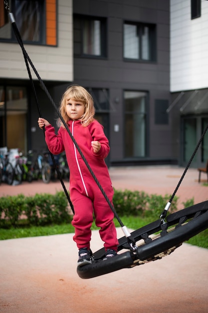 klein meisje in rode kleren zwaaiend op een schommel