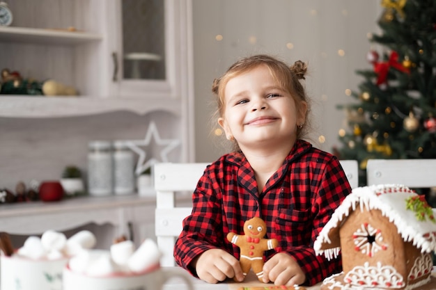 klein meisje in rode pyjama met versierde kerstkoekjes voor peperkoekmannen