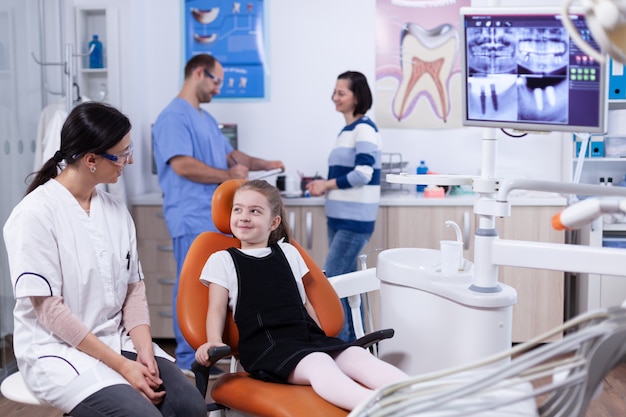 Klein meisje in stomatologie kantoor wachten op haar tanden medische procedure en onderzoek. Kind met haar moeder tijdens tandencontrole met stomatolog zittend op een stoel.