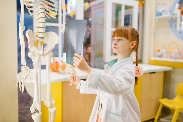 Klein meisje in uniform kijkt naar de x-ray, arts spelen