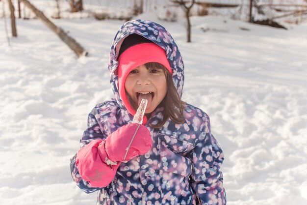 Klein meisje in winterkleren proef het ijs